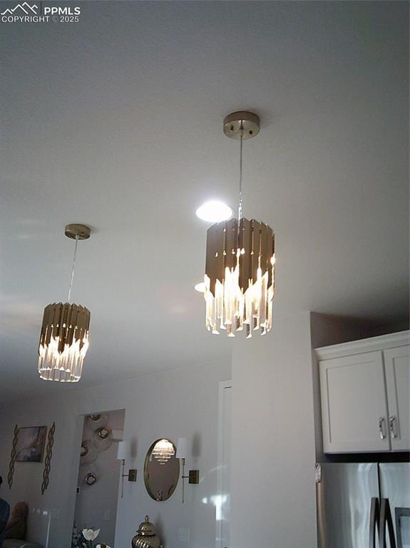 details with a chandelier, pendant lighting, stainless steel fridge with ice dispenser, and white cabinetry