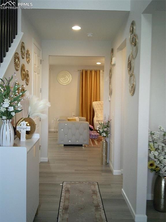 corridor featuring baseboards, recessed lighting, and light wood-style flooring