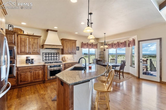 4908 Silver Nell Dr, Colorado Springs, CO 80908 - kitchen featuring appliances with stainless steel finishes, premium range hood, and brown cabinets