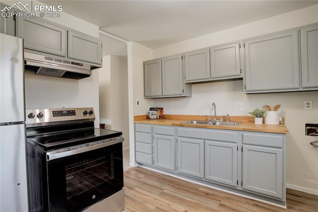409 Columbine St, Fountain, CO 80817 - kitchen featuring appliances with stainless steel finishes, a sink, under cabinet range hood, gray cabinetry, and light wood-type flooring