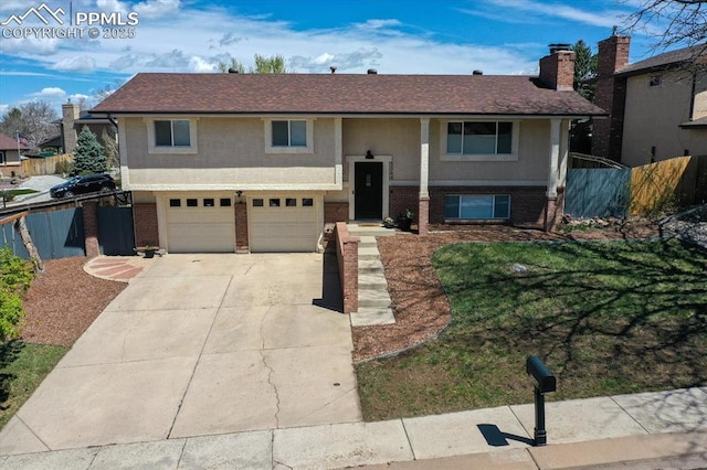 5064 Artistic Cir, Colorado Springs, CO 80917 - split foyer home featuring fence, an attached garage, concrete driveway, and brick siding