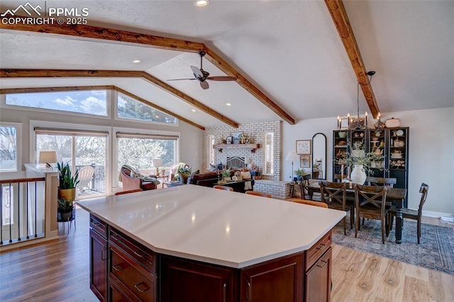 kitchen with light countertops, light wood-style flooring, open floor plan, and lofted ceiling with beams