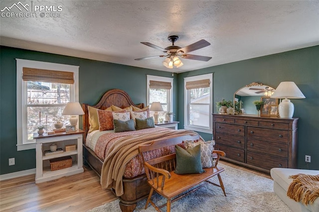 bedroom with baseboards, a ceiling fan, wood finished floors, and a textured ceiling