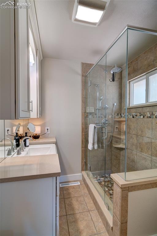 full bath with a shower stall, vanity, tile patterned floors, and baseboards