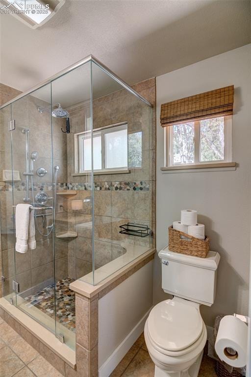 bathroom with tile patterned floors, baseboards, toilet, and a stall shower