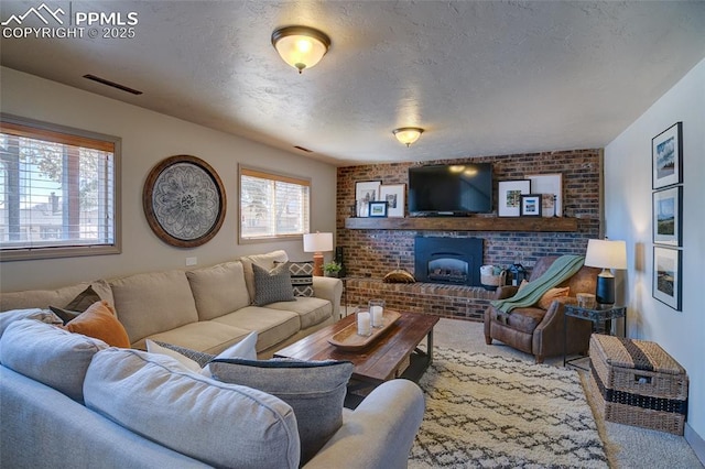 living area featuring brick wall, a brick fireplace, visible vents, and a textured ceiling
