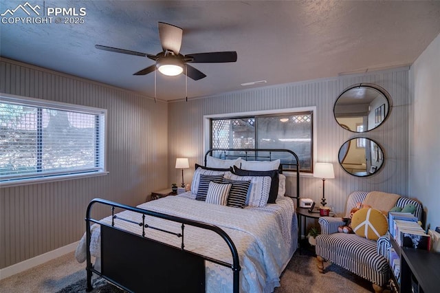 bedroom featuring wooden walls, carpet flooring, baseboards, and ceiling fan