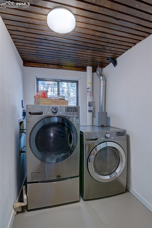 washroom with washing machine and clothes dryer, wooden ceiling, baseboards, and laundry area