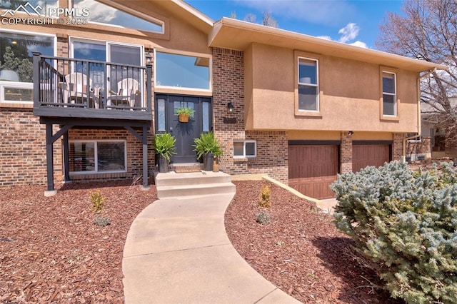 view of front of home with brick siding, a balcony, a garage, and stucco siding