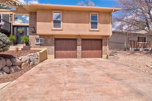 view of front of property with an attached garage, stucco siding, brick siding, and decorative driveway