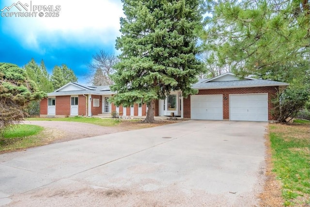 view of front facade featuring an attached garage, driveway, a front lawn, and brick siding