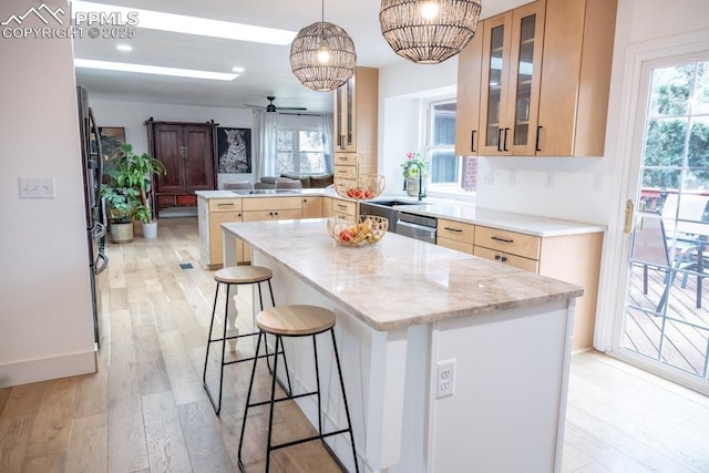 kitchen with light brown cabinetry, a peninsula, a sink, and dishwasher