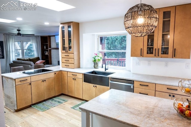 kitchen featuring black electric stovetop, a sink, a peninsula, light wood-type flooring, and stainless steel dishwasher