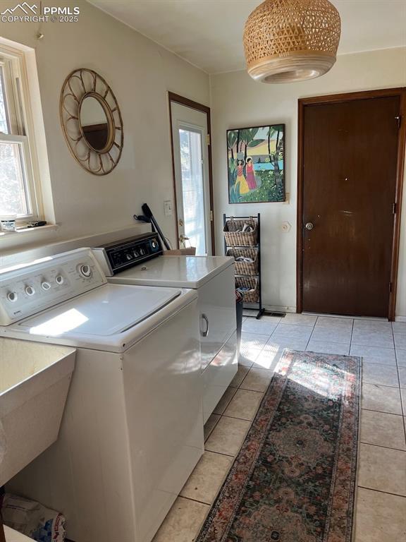 clothes washing area featuring laundry area, plenty of natural light, light tile patterned floors, and separate washer and dryer