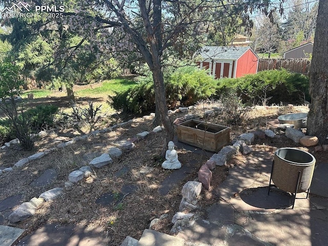 view of yard with an outdoor structure, fence, and a shed