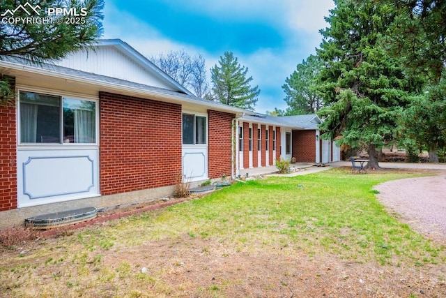 view of front facade featuring an attached garage, a front yard, and brick siding