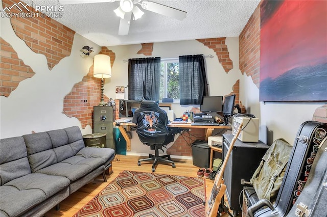 4230 Hollow Rd, Colorado Springs, CO 80917 - home office with a ceiling fan, a textured ceiling, wood finished floors, and brick wall