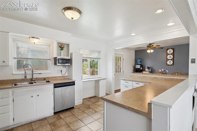 kitchen with white cabinetry, a sink, appliances with stainless steel finishes, ceiling fan, and baseboards