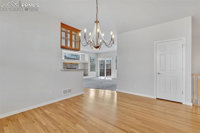 16850 Buffalo Valley Path, Monument, CO 81032 - unfurnished dining area with a chandelier, visible vents, light wood-style flooring, and baseboards
