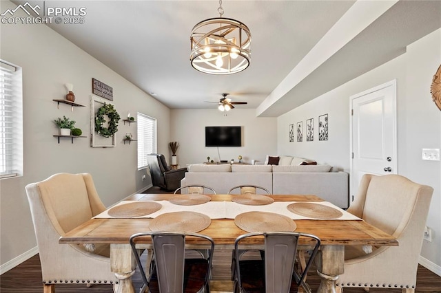 dining space with baseboards, dark wood-type flooring, and ceiling fan with notable chandelier