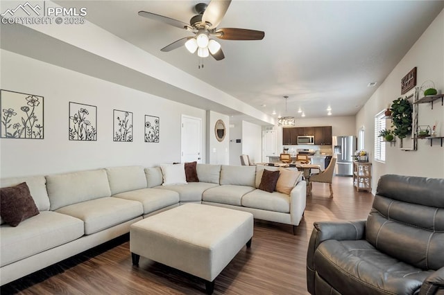 living room with dark wood-style floors and ceiling fan with notable chandelier