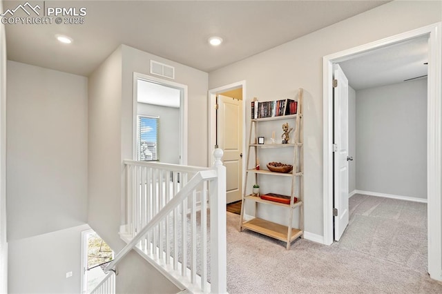 corridor featuring baseboards, recessed lighting, visible vents, carpet, and an upstairs landing