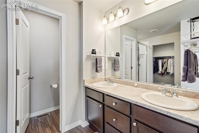 full bath featuring a walk in closet, wood finished floors, a sink, and visible vents