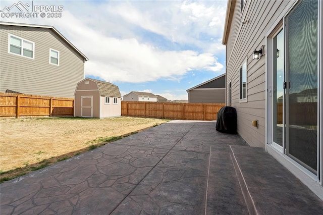 view of patio / terrace with a fenced backyard, a storage unit, and an outbuilding