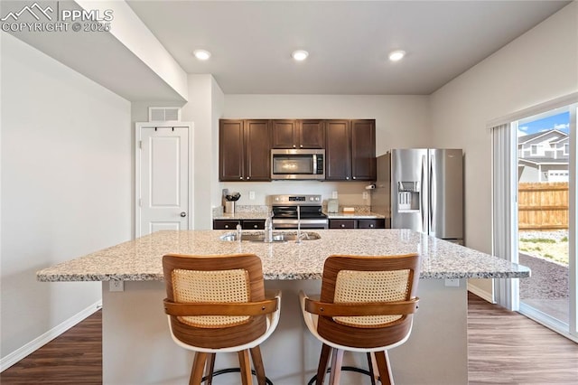kitchen featuring baseboards, dark brown cabinetry, stainless steel appliances, and dark wood-type flooring