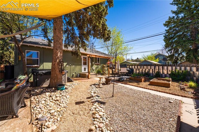 413 E Fontanero St, Colorado Springs, CO 80907 - back of property with a patio area, a vegetable garden, fence, a jacuzzi, and stucco siding