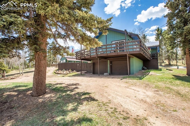 555 Elfin Glen Dr, Divide, CO 80814 - back of property featuring a deck, dirt driveway, an attached garage, and fence