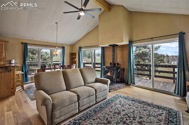 555 Elfin Glen Dr, Divide, CO 80814 - living room with high vaulted ceiling, a wood stove, ceiling fan, a textured ceiling, and light wood-style floors