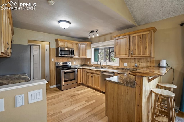 555 Elfin Glen Dr, Divide, CO 80814 - kitchen with appliances with stainless steel finishes, a peninsula, a sink, light wood-style flooring, and a breakfast bar