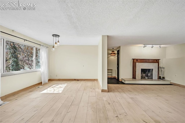 1624 Cheyenne Blvd, Colorado Springs, CO 80906 - unfurnished living room with baseboards, a fireplace with raised hearth, and a textured ceiling