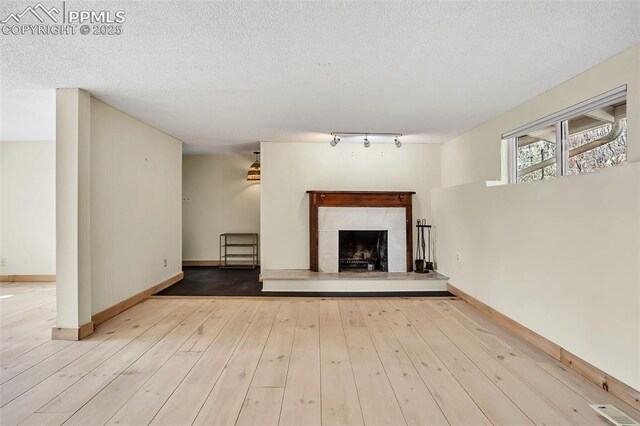 1624 Cheyenne Blvd, Colorado Springs, CO 80906 - unfurnished living room featuring a premium fireplace, rail lighting, baseboards, wood finished floors, and visible vents