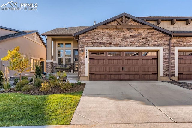 view of front of house featuring an attached garage, driveway, and stone siding