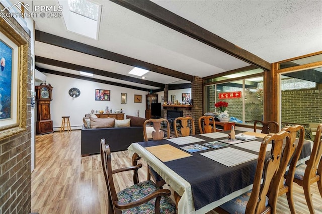 dining room with beam ceiling, a baseboard radiator, light wood-style flooring, and a fireplace