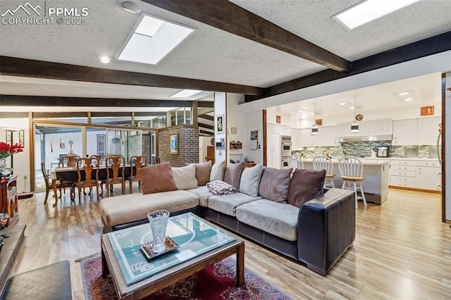 living area with a textured ceiling, light wood-style flooring, and beam ceiling