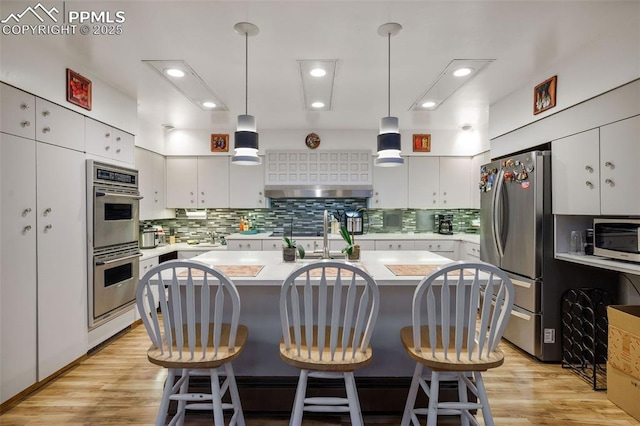kitchen with light countertops, backsplash, appliances with stainless steel finishes, and a sink