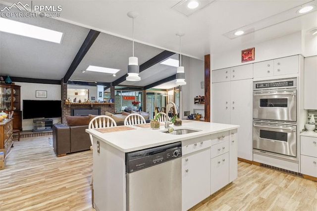 kitchen with white cabinets, appliances with stainless steel finishes, a sink, light wood-style floors, and light countertops