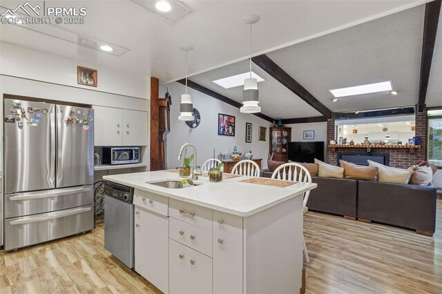 kitchen featuring a sink, light countertops, light wood finished floors, stainless steel appliances, and white cabinetry