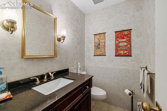 bathroom featuring tile patterned flooring, vanity, toilet, a wainscoted wall, and visible vents