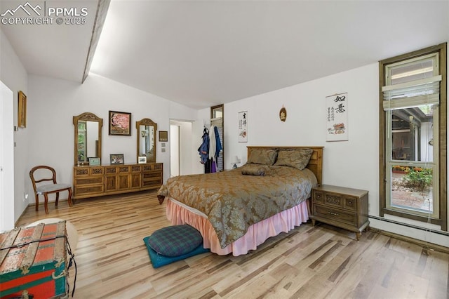 bedroom with a closet, a baseboard heating unit, and light wood-type flooring