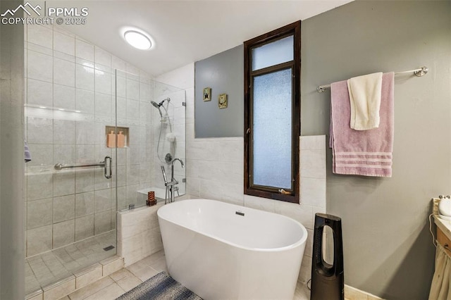 bathroom featuring vanity, tile walls, tile patterned floors, a soaking tub, and a stall shower