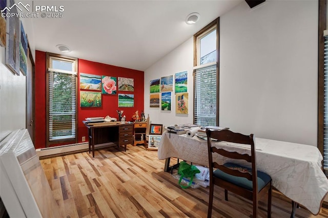interior space with light wood-style flooring, lofted ceiling, and a baseboard heating unit