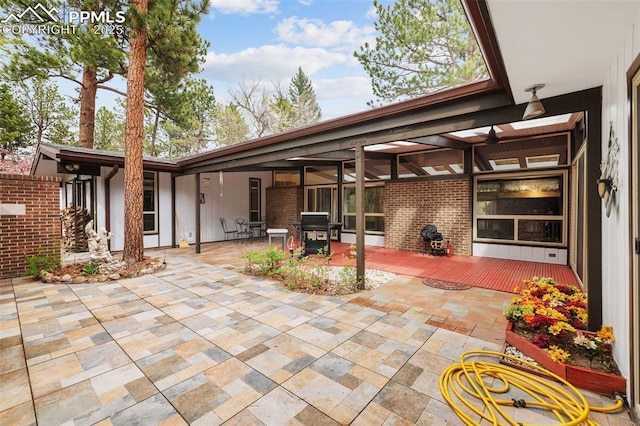 exterior space with brick siding, a deck, and a patio area
