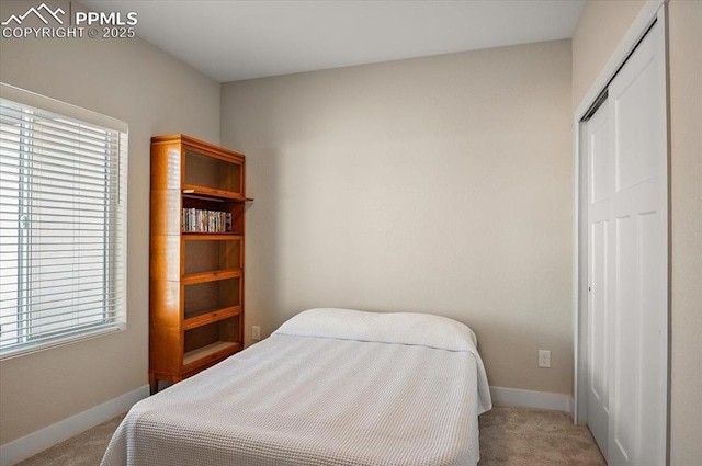 bedroom with a closet, light colored carpet, and baseboards