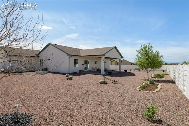 rear view of property featuring a fenced backyard, stucco siding, and a patio area