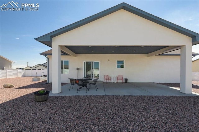 rear view of property featuring a patio, stucco siding, and fence