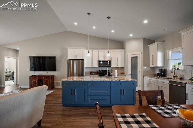 kitchen with open floor plan, stainless steel appliances, white cabinets, and dark wood-style floors
